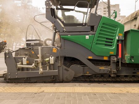 Tracked paver. Industrial pavement truck laying fresh asphalt on construction site. Asphalt a new on...