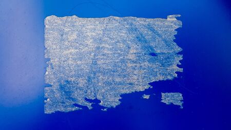 Blue shabby paint background on rusty iron. Blue metal wall with a rectangular white trace from the sticker in the centerの写真素材