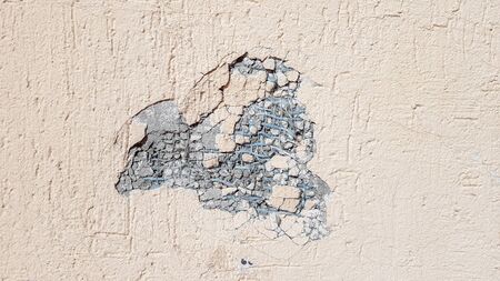 dent on a yellow concrete wall. Hole in the wall with foam insulation. Crack on the yellow wall with...