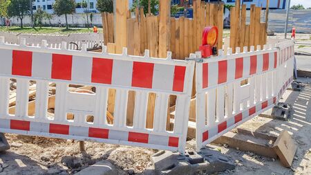 Plastic Protective barrier fences the site of road work. Red and white plastic fence near the street repair site. Construction work on the street, road repair, protective fence.の写真素材