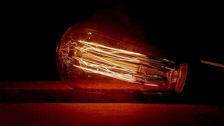 Vintage hanging edison light bulb on a dark background. Old dusty light bulbs glowing in the dark. A...
