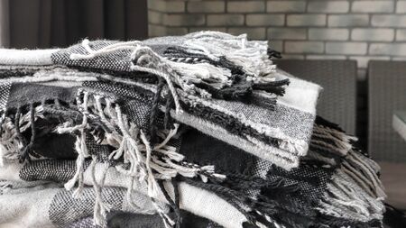 heap of knitted plaids on a gray background. Warm and cozy woolen decor for home and cafe. Gray wall...