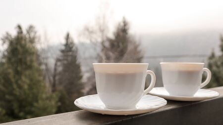 Two coffee cups on a balcony with mountain landscape in the morning. Two cups of morning coffee,...