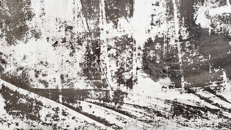 Weathered and aged concrete wall with paint, mostly peeled from black and white with vignetting....