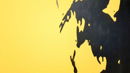 Black abstract paint splashes dripping on a bright yellow background. Black paint splashes on a...