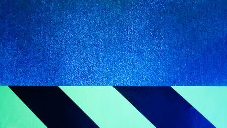 diagonal yellow and black stripes on a blue problem wall. Abstract colorful minimalist pattern....