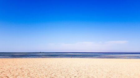 A beautiful sandy beach without people and a tropical blue sea with blue sky backgroundの写真素材