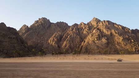 Desert in Egypt. Rocky sand hills. A lone tourist on an ATV in the desert against the background of blue sky and mountains is walking towards the Red Sea. Landscape in the desertの写真素材