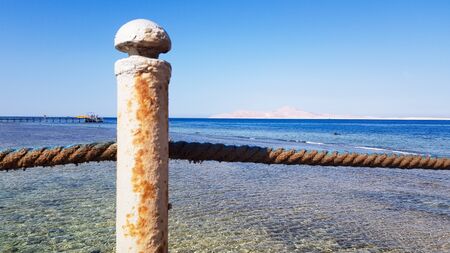 Long pontoon on the Red Sea in Egypt. Pontoon for descent into the water. Wooden bridge on the territory of the Amway Hotel in Sharm El Sheikh with metal fences and a rope over the sea with waves.の写真素材