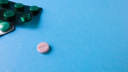 Two packs of pills and one round pill to the side on a blue background with copy space. antiviral...