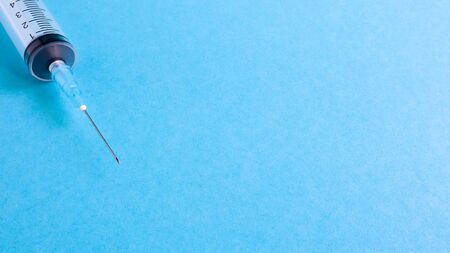 On a blue background lies a medical syringe with a needle. epidemic. Copy space The concept of collecting blood and injection vaccines, medical equipment for hypodermic injection, healthcare themeの写真素材