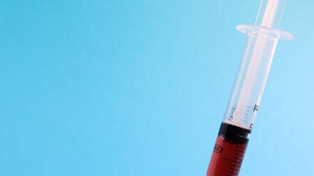 On a blue background lies a medical syringe with a needle. epidemic. Copy space The concept of collecting blood and injection vaccines, medical equipment for hypodermic injection, healthcare themeの写真素材