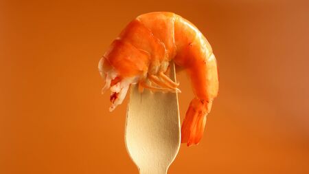 One large king cooked shrimp in the sink on a wooden fork on a brown background. Infrastructure of crustaceans of the decapod, eating carrion. Sea delicacy. Shrimp is used in cooking. Beer snack.の写真素材