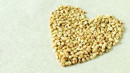 Heart made of green buckwheat. Symbol of love and health. Great food. healthy groats. Organic raw non-fried vegetarian food. The concept of a healthy, balanced and dietary diet. Copy space.の写真素材