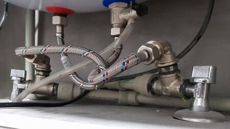 Connection of water supply, hot and cold water to the boiler. Hose for hot and cold water in the bathroom. Plumbing connections for a domestic electric water heaterの写真素材
