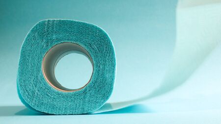 Blue roll of modern toilet paper on a blue background. A paper product on a cardboard sleeve, used for sanitary purposes from cellulose with cutouts for easy tearing. Embossed drawing.の写真素材