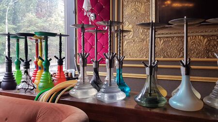 Group of modern glass hookah appliance on a wooden stand. Restaurant bar. Glass hookahs on the bar...