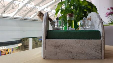 A table in a cafe or restaurant. Napkins in a wooden napkin holder, spices salt and pepper, olive...