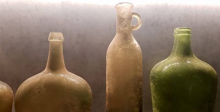 large vintage vases or jugs of colored glass as decoration elements in a modern interior near a gray concrete wall. Decoration of an apartment or houseの写真素材