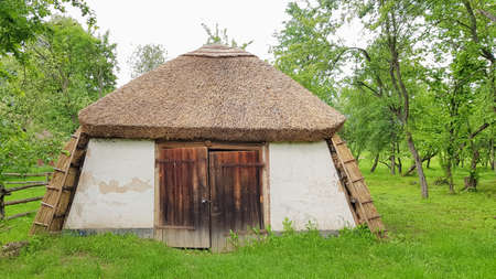 Ukraine, Kiev - June 11, 2020. Old peasant Ukrainian house or barn in the summer with a thatched roof in the village. Pirogovo Museum in the open air of different regions of Ukraineのeditorial素材