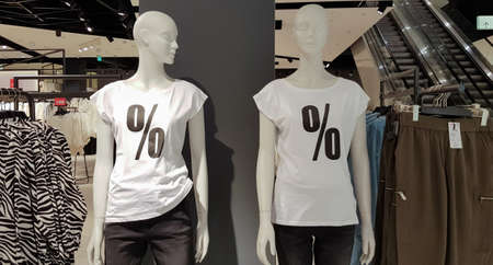Mannequins dressed in white T-shirts with a percent sale sign in a shopping mall for shopping....