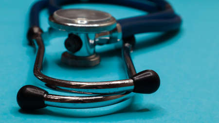 Old shabby stethoscope on a blue background.の写真素材