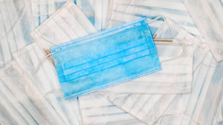 Coronavirus protection. Many antiviral protective medical face masks with ear loops spread out on a blue background. Surgical mask background. Respiratory syndrome, coronavirus disease COVID-19の写真素材