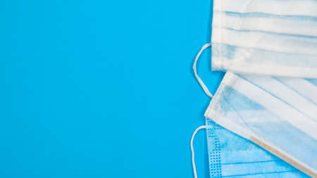 Three disposable surgical face masks with rubber pads to cover the mouth and nose on a blue...
