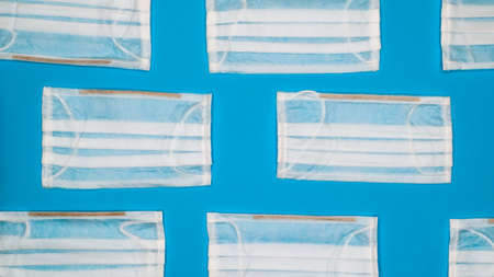 Coronavirus protection. Many antiviral protective medical face masks with ear loops spread out on a...