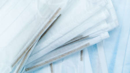 Coronavirus protection. Antiviral protective medical face masks with ear loops. Surgical mask background. Respiratory syndrome, coronavirus disease COVID-19. Many folded medical masksの写真素材