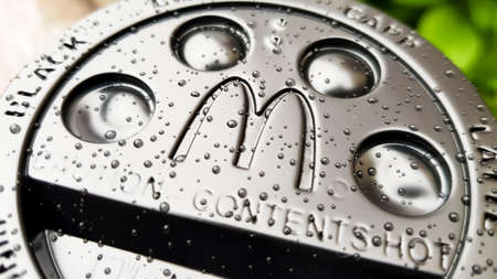 Close-up of McDonald's fast food restaurant logo on a black paper cup lid with hot McCafe coffee....
