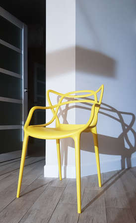 Yellow plastic chair near the wall with a shadow in the interior of the houseの写真素材