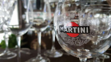 Martini glasses are in the bar. The inscription on the glass and the logo martini sticker. Focus and color concept. A brand of Italian-made vermouths and sparkling wines. Italy, Turin - October 1, 2020のeditorial素材