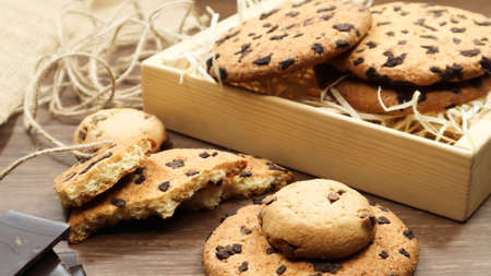 American chocolate chip cookies on a brown wooden table close-up in a box. Traditional rounded...