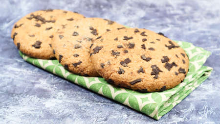 American chocolate chip cookies on a green napkin on a gray background. Traditional round crispy...
