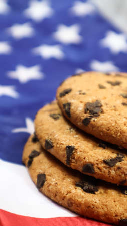 Patriotic cookies. Three rounded traditional chocolate chip cookies on the background of the flag of the United States of America. Delicious sweet pastries, dessert. America's favorite treatの写真素材