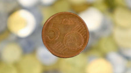A close-up shows one 5 euro cent coin. This is money. Blurred money background. Changeable...