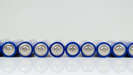 Lots of AA alkaline batteries on a white glossy background with reflection with copy space lined up in one lineの写真素材
