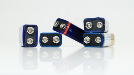 Five blue used, chaotically laid out and scattered PP3 batteries on a white background with reflection. Main battery for personal power supplies. Close-up of a scratched and used battery connectorの写真素材