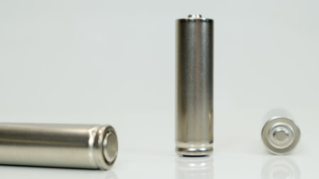 AA alkaline rechargeable batteries on white glossy background with reflection. Close up three empty...