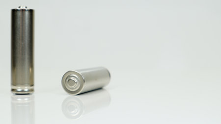 AA alkaline rechargeable batteries on white glossy background with reflection. Close up two empty batteries with copy spaceの写真素材