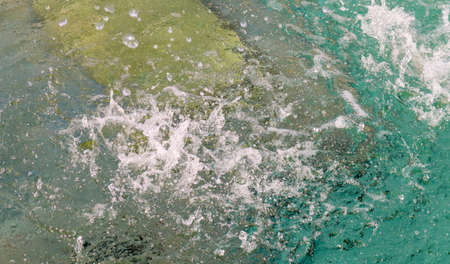Frequent drops of water in a fountain in slow motion fall on a clean water surface with splashes and...