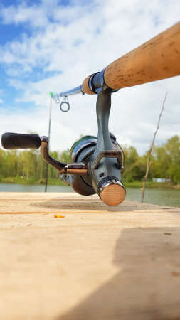 Carp fishing rod isolated on the lake and wooden bridge. Carp feeder spinning reel close up. Fishing...