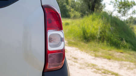 Right rear headlight. The rear of a small passenger hatchback or SUV of a white car with a group of...