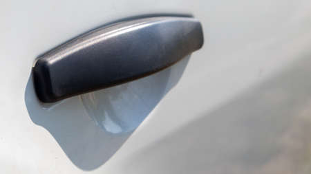 Black plastic door handle of a modern white car. Transport. Detail and part of the car. Door opening handle from outsideの写真素材