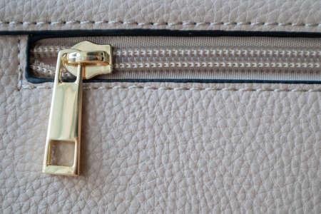 Natural or artificial leather texture. Fragment of a beige or powdery bag with a zipper and stitching. Zipper or clasp bag design element. Bovine skin texture with snake. Macro photo, selective focusの写真素材