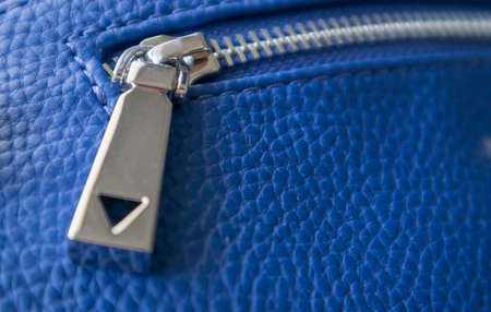 Natural or artificial leather texture. Fragment of a blue bag with a zipper and stitching. Zipper or clasp bag design element. Bovine skin texture with snake. Macro photo, selective focusの写真素材
