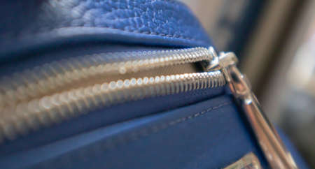 Natural or artificial leather texture. Fragment of a blue bag with a zipper and stitching. Zipper or clasp bag design element. Bovine skin texture with snake. Macro photo, selective focusの写真素材