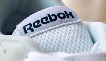 Sign on Reebok shoes. One of the world's largest sportswear and footwear companies. New white sneakers with Reebok logo. The concept of sports and casual shoes. Ukraine, Kiev - June 18, 2021のeditorial素材