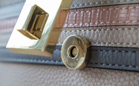 Close-up of a gold magnetic button-lock of an open elegant womens fashionable beige leather shoulder bag. Accessories, detailの写真素材
